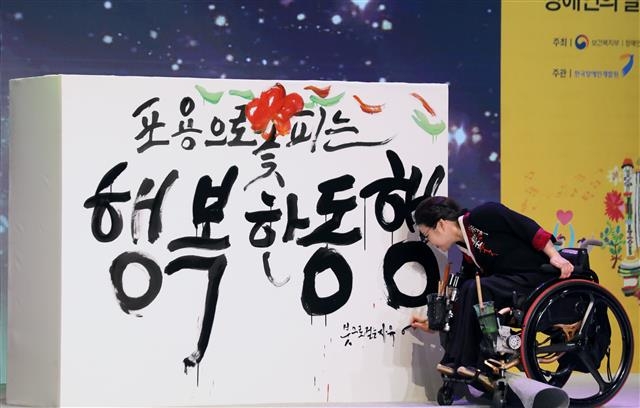 18일 서울 영등포구 여의도 63빌딩에서 열린 ‘제39회 장애인의 날 기념식’에서 캘리그라피 작가 이은희씨가 붓으로 ‘포용으로 꽃피는 행복한 동행’이라는 문구를 쓰는 기념공연을 하고 있다. 뉴스1
