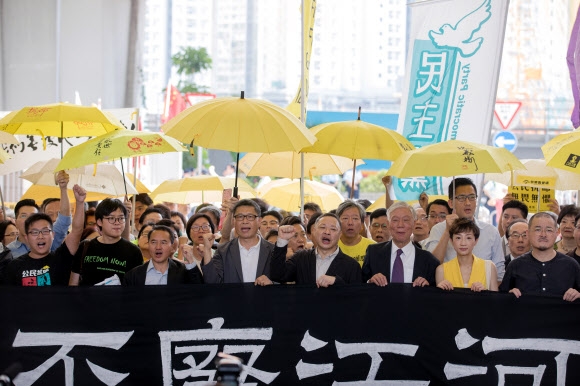홍콩 법원이 2014년 민주화 시위 ‘우산 혁명’을 이끈 지도자들에게 공중방교죄(공공소란죄)를 적용해 최대 징역 16개월을 선고한 가운데, 찬킨만(앞줄 왼쪽) 홍콩중문대 교수 등 시위 주역들이 지지자들과 함께 구호를 외치고 있다. 홍콩 AFP 연합뉴스