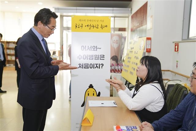 김영종 서울 종로구청장이 지난 24일 장애인의 날 기념행사가 열린 종로장애인복지관 로비에서 자원봉사자로부터 수화를 배우고 있다.  종로구 제공 김영종 서울 종로구청장이 지난 24일 장애인의 날 기념행사가 열린 종로장애인복지관 로비에서 자원봉사자로부터 수화를 배우고 있다.  종로구 제공