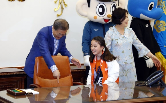 문재인 대통령이 어린이날인 5일 오전 청와대 집무실에서 초청한 어린이들과 기념촬영을 하기에 앞서 한 어린이에게 대통령 자리에 앉을것을 권하고 있다. 이날 청와대는 강원도 산불진화 소방관, 군인, 경찰 자녀와 산불 피해 초등학교 학생 및 아동정책 수혜 아동, 독립유공자 후손 등 총 180명의 어린이를 청와대로 초청해 행사를 열었다. 2019.5.5 연합뉴스