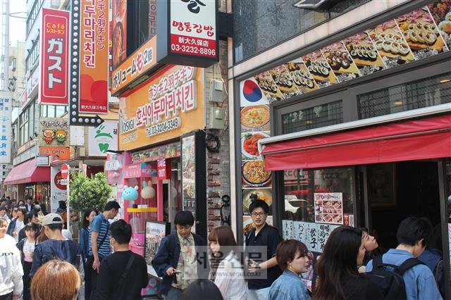 일본 도쿄 신주쿠 신오쿠보 거리의 한 분식 전문점 앞에 일본인들이 줄을 서 있다. 그 옆으로 한글 상호 간판을 크게 내건 음식점도 보인다.