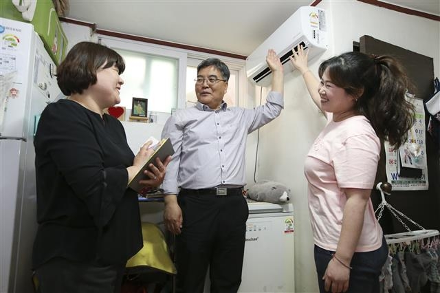 서울 종로구 윤경임(왼쪽부터) 온마을돌봄팀장, 권오선 여성가족과장, 이영빈 주무관이 지역 내 아동을 둔 취약계층 가구를 방문해 에어컨 설치를 마친 뒤 시험 가동해 보고 있다. 종로구 제공