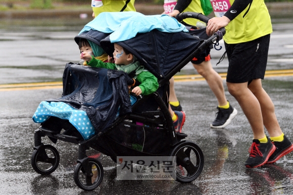 19일 쏟아지는 빗줄기 속에서 가족 단위 참가자가 여럿 눈에 띄었다. 한 남성이 유모차를 탄 두 아이와 레이스를 즐기는 모습. 박윤슬 기자 seul@seoul.co.kr