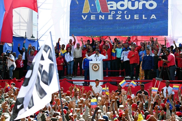 니콜라스 마두로 베네수엘라(가운데) 대통령이 20일(현지시간) 수도 카라카스에서 재선 승리 1주년 기념 집회에서 붉은색 셔츠를 입은 지지자들을 향해 조기 총선을 치를 것이라고 밝히고 있다. 2019.05.20 카라카스 AP 연합뉴스