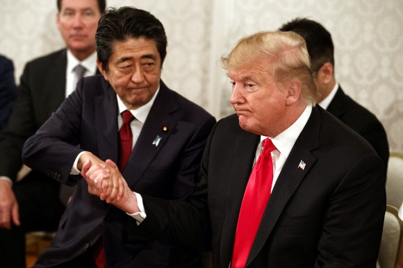 도널드 트럼프 미국 대통령이 27일 일본 도쿄 아카사카 궁전에서 북한에 납치된 피해자 가족을 만나 접견하다 아베 신조 총리와 손을 맞잡고 있다. 도쿄 AP 연합뉴스 
