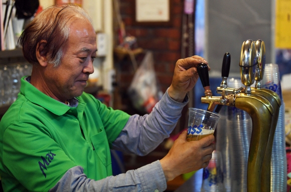 ‘을지OB’ 창업주 강효근옹의 사위 최수영(64)씨가 냉장 숙성한 맥주를 잔에 따르고 있다