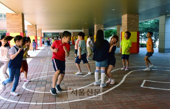 지난달 31일 서울 동작구 영화초등학교 학생들이 블록 수업 뒤 이어진 20분짜리 중간휴식시간에 학교 건물 1층 필로티 공간에 그려진 8자 모양 도형을 따라 뛰어다니면서 잡기 놀이를 하고 있다. 안전을 위해 기둥에 충격 방지 완충재가 설치된 점이 눈에 띈다.  이종원 선임기자 jongwon@seoul.co.kr