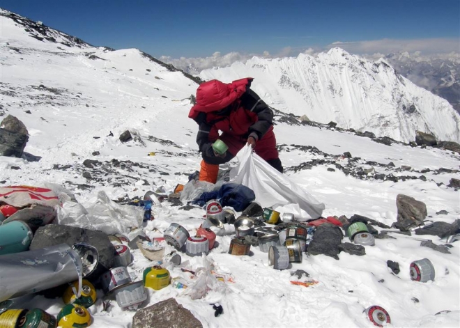 한 네팔인이 2014년 에베레스트산 등산 캠프 주변에 쌓여있는 쓰레기를 치우고 있다.  NBC 뉴스 화면 캡처