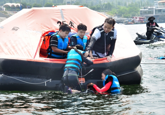 지난 5일 서울교육청이 주관하는 ‘안심 생존수영 교육’에 참가한 서울 신영초 5학년 학생들이 잠실야외수영장 앞 한강에서 생존수영 실습을 하고 있다. 한 학생이 친구들과 기자의 도움을 받아 한강 위에 띄워 놓은 구명벌에 오르고 있다. 이종원 선임기자 jongwon@seoul.co.kr