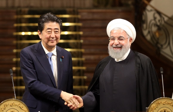 이란을 방문한 아베 신조(왼쪽) 일본 총리와 하산 로하니 이란 대통령이 12일(현지시간) 테헤란 사드 아바드 궁에서 정상회담에 이은 공동기자회견을 마친 뒤 악수를 하고 있다. 테헤란 EPA 연합뉴스