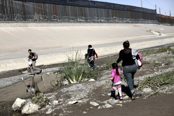 미국으로 향하는 중미 출신 불법 이민자 가족이 15일(현지시간) 멕시코 북부 시우다드후아레스와 미 텍사스주 앨패소 사이의 국경을 넘기 위해 리오 브라보 강을 건너고 있다. 2019.06.16 앨패소 AP 연합뉴스