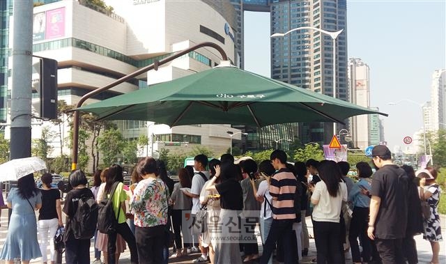 신도림역 삼거리 횡단보도에서 신호를 기다리는 시민들이 초여름 뜨거운 햇볕을 피해 그늘막에 빼곡히 들어서 있다.