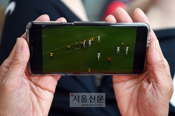 유정규 선수가 자신이 운영하는 부동산에서 짬을 내어 휴대폰으로 U20 월드컵 경기 하이라이트를 시청하고 있다.