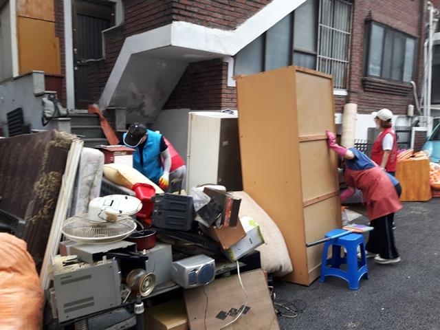 강동구 암사1동의 한 독거 어르신 집에서 구 직원들이 쓰레기를 치우고 벽지와 장판을 새로 교체하기 위해 가구를 밖으로 옮기고 있다. 강동구 제공