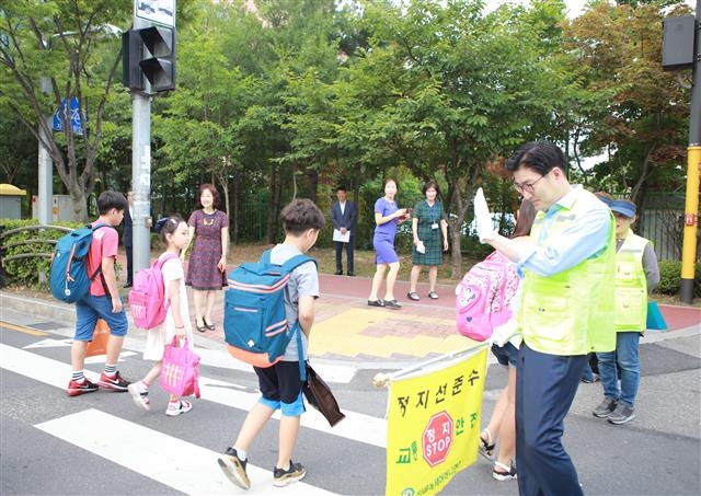 민선 7기 1주년을 맞은 지난 1일 서울 구청장들이 기념식 대신 민생 행보에 나섰다. 이정훈(오른쪽) 강동구청장이 강일초등학교 앞 횡단보도에서 아이들이 안전하게 등교할 수 있도록 지도하고 있다. 강동구 제공