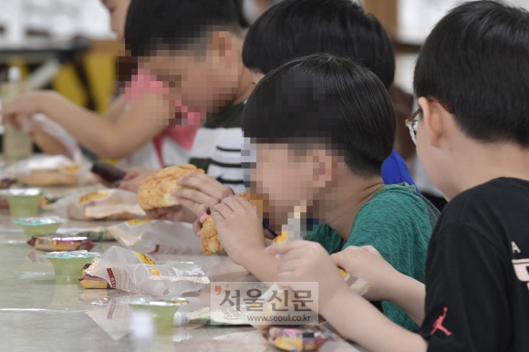 급식 조리원과 돌봄 전담사 등 학교 비정규직 노동자들이 총파업에 들어간 3일 급식이 중단된 서울 시내 한 초등학교 급식실에서 학생들이 대체 급식으로 나온 빵과 주스 등을 먹고 있다. 2019. 07.03.  박윤슬 기자 seul@seoul.co.kr