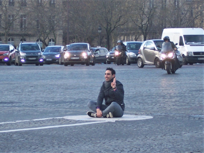 한 남성이 차량들이 신호 대기 중인 도로 한복판에 앉아 사진을 찍고 있다. 　플리커 　 