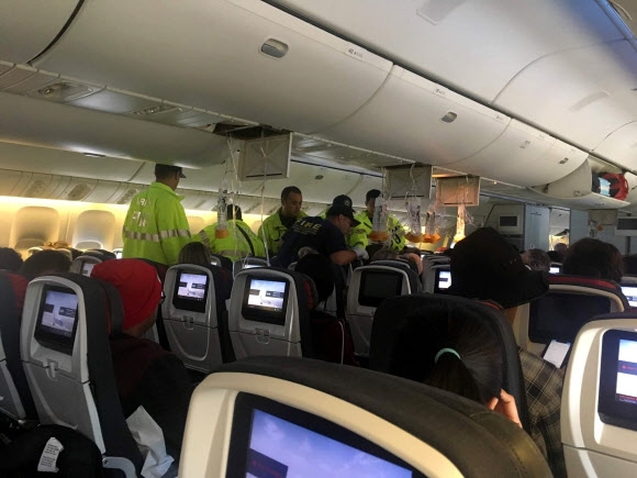 호놀루루 긴급구조대가 12일 비상착륙한 에어 캐나다 AC 32편에 올라 마른 하늘 터뷸런스에 부상을 입은 승객들을 후송하고 있다. 곳곳에 산소 마스크가 충격에 떨어져 내려와 있다. 호놀루루 소셜미디어 캡처 로이터 연합뉴스