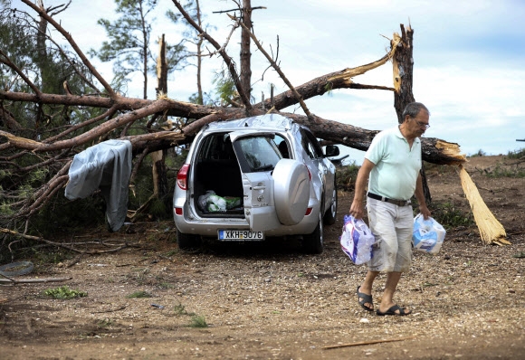 그리스 할키디키에서 11일(현지시간) 한 남성이 폭풍우로 인해 나무에 깔린 차량에서 물건들을 챙겨 나오고 있다. 할키디키 AP 연합뉴스