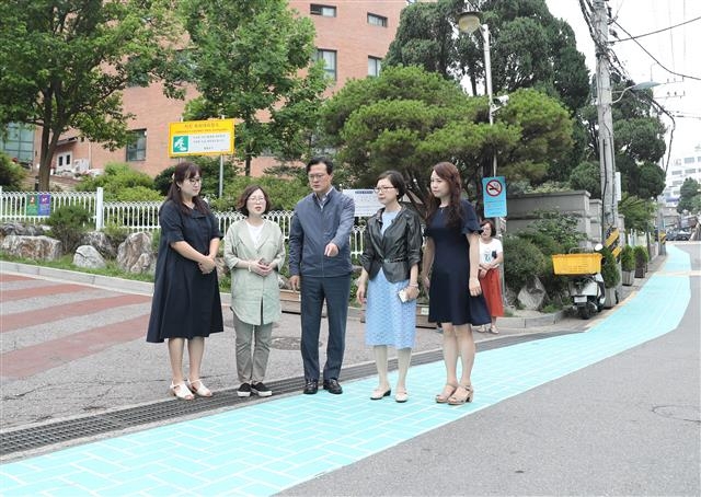채현일(가운데) 영등포구청장이 지난달 27일 서울 영등포구 영등포여고 정문 앞에 설치된 유색포장도로를 학교 관계자들과 함께 살펴보고 있다. 영등포구 제공