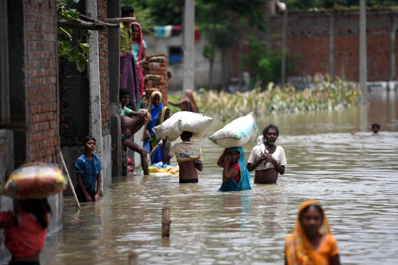 몬순 홍수에 허리춤까지 물에 잠긴 인도 비하르 시타마르히에서 17일(현지시간) 주민들이 머리에 짐을 인 채 이동하고 있다. 이번 홍수로 인도를 비롯한 남아시아 지역에서만 최소 300여명이 사망하고 수백만명의 이재민이 발생했다. 시타마르히 AFP 연합뉴스