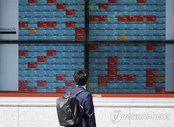 일본 도쿄의 한 증권사 앞에서 한 남성이 개별 종목 주가가 표시된 전광판을 보고 있다. AP 연합뉴스 자료사진