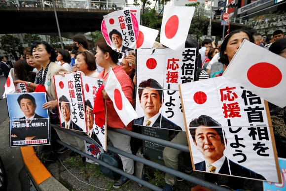 일본 참의원 선거 하루 전인 지난 20일 도쿄에서 열린 마지막 유세에서 아베 신조 총리가 집권 자민당 후보들의 지지 연설을 하기에 앞서 지지자들이 ‘아베 총리를 응원한다’는 플래카드와 사진을 들고 환호하고 있다. 도쿄 AFP 연합뉴스