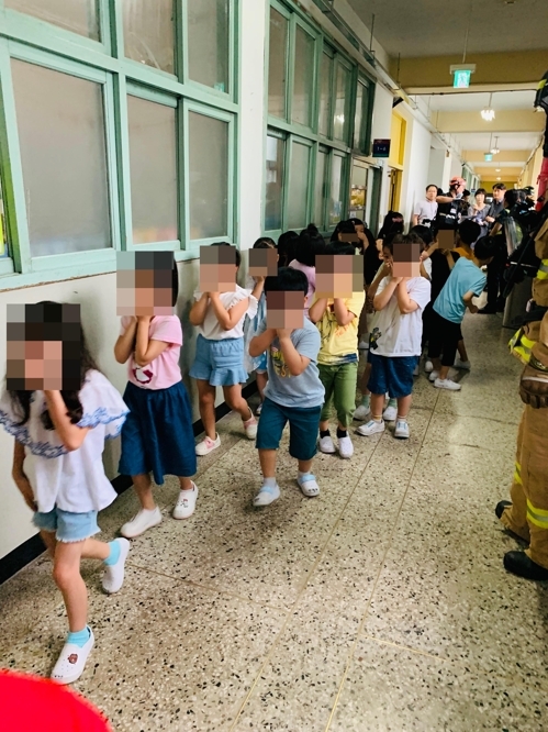 25일 서울 구로구의 한 초등학교에서 학생들이 코와 입을 가린 채 건물 밖으로 대피하고 있다. 2019.7.25  구로소방서 제공