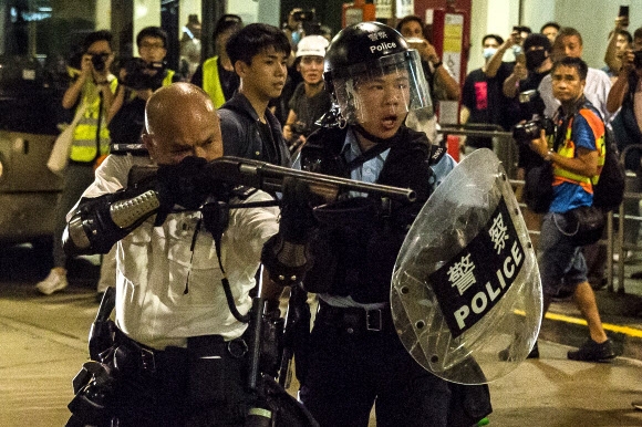 지난 주말 ‘범죄인 인도 법안’(송환법) 반대 시위 참가자 중 일부가 폭동죄로 기소된다는 소식에 분노한 수백 명의 홍콩 시민들이 30일 시위 참가자들을 구금 중인 콰이청 경찰서 앞에서 항의 시위를 벌이자 경찰이 산탄총처럼 보이는 총으로 시위대를 겨냥하고 있다. 폭동 혐의가 적용되면 최고 10년 징역형을 받을 수 있어 큰 파문이 예상된다. 홍콩 AFP 연합뉴스