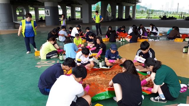 서울 구로구의 중·고등학교 학생들이 지난달 29일 안양천변에 모여 앉아 하천 수질 개선에 도움을 주는 EM 흙공 만들기 봉사를 하고 있다. 구로구 제공