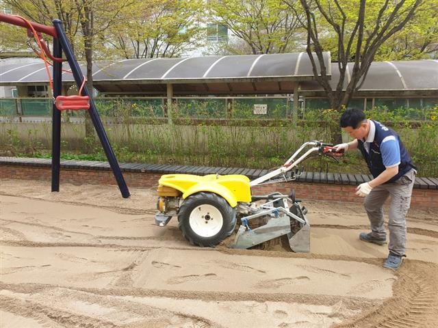 지난 4월 서울 동작구 상도동의 한 아파트 어린이 놀이터에서 구청 직원이 모래의 이물질을 제거하고 바닥을 평탄하게 고르는 작업을 하고 있다. 동작구 제공