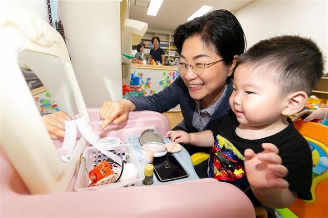 지난달 24일 오후 서울 은평구 응암동 대림시장을 찾은 김미경 구청장이 엄마가 장을 보러 간 사이 ‘아이조아 돌봄 나눔터’에 맡겨진 아이와 놀아 주며 웃고 있다. 은평구 제공