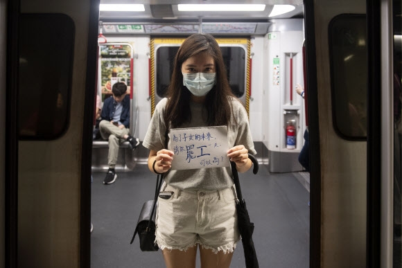 5일 홍콩 지하철(MTR) 다이아몬드 힐역에서 마스크를 한 여성 시위자가 “당신 자녀들의 미래를 위해 총파업에 동참해달라”라는 플래카드를 들고 시위를 벌이고 있다. 홍콩 EPA 연합뉴스