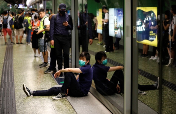 5일 홍콩 MTR 포트리스 힐역 플랫폼에서 마스크를 한 남성 시위자가 지하철의 운행을 방해하기 앉아 있다. 홍콩 로이터 연합뉴스