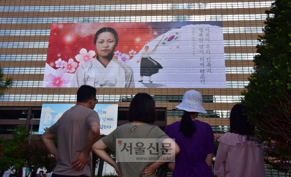 광복절을 앞둔 11일, 서울 종로구 교보생명빌딩 외벽에서 유관순 열사의 모습을 담은 초대형 래핑(Wrapping)작업을 하고 있다. 이번 래핑은 대한민국 임시정부 수립 100주년을 맞아 독립의 의미를 되새기고 독립열사의 숭고한 희생을 기리기 위해 제작됐다. 2019.8.11.    이종원 선임기자 jongwon@seoul.co.kr