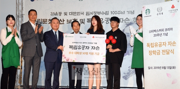 13일  서울 덕수궁 중명전에서 열린 ‘독립문화유산 보호 및 독립유공자 자손 후원 행사’에서 송호섭 스타벅스코리아 대표가 독립유공자 자손에게 장학금을 전달하고 있다. 2019.8.13 정연호 기자 tpgod@seoul.co.kr