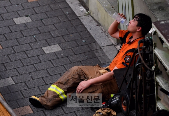 15일 오전 서울 중구 남대문오피스텔에서 발생한 화재를 진압하던 소방대원들이 작업 도중 휴식을 취하고 있다. 2019.8.15  박지환기자 popocar@seoul.co.kr