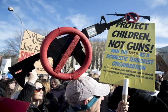 지난해 3월 24일 워싱턴DC에서 열린 총기 사용 반대 시위에 참가한 한 시민이 총기 금지 조형물을 쓴 채 ‘총이 아닌 아이들을 지켜라’는 내용의 피켓을 들고 있다. 워싱턴 EPA 연합뉴스
