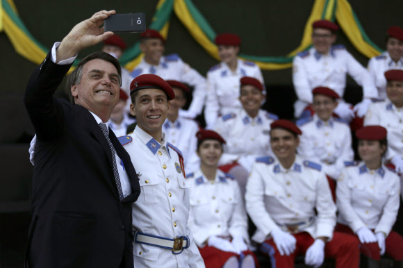 산불 진화에 앞장서야 할 자이르 보우소나루 브라질 대통령은 23일(현지시간) 군인의 날 퍼레이드 행사에 앞서 군사학교 학생들과 셀피를 찍느라 여념이 없다. 브라질리아 AP 연합뉴스 
