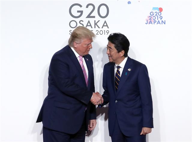 지난 6월 오사카에서 열린 G20 정상회의 의장국인 일본의 아베 신조(오른쪽) 총리가 도널드 트럼프 미국 대통령과 공식환영식에서 악수하고 있다. 연합뉴스