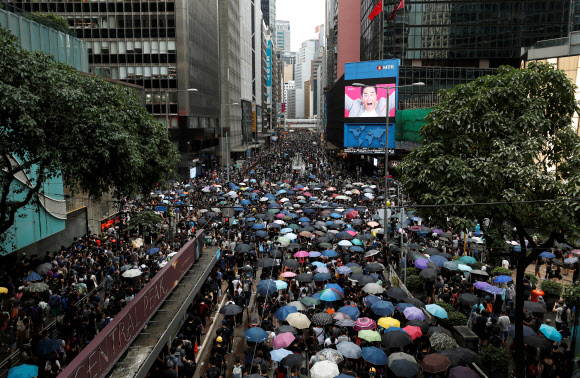 시위대가 31일(현지시간) 홍콩 중심가에서 ‘범죄인 인도 법안(송환법)’ 철폐와 민주화를 요구하며 우산을 쓰고 거리 행진을 하고 있다. 로이터 연합뉴스