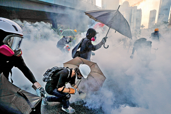 15일(현지시간) 홍콩 센트럴 지역의 정부청사 일대에서 ‘범죄인인도법안’(송환법) 반대 시위에 나선 시민들이 경찰의 최루탄 공세를 피하기 위해 우산을 펼쳐 들고 있다. 홍콩 로이터 연합뉴스