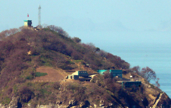 24일 인천 강화군 서도면 말도에서 바라본 함박도의 모습. 산 정상 위에 레이더 시설인 철탑이 있고 그 왼편에 있는 감시시설에 인공기가 보인다. 사진공동취재단