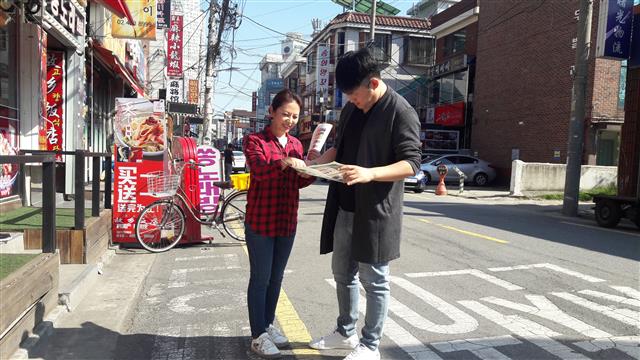 서울 광진구 자양4동주민센터에 채용된 중국 헤이룽강 출신의 장유진(왼쪽) 주무관이 지난 24일 자양4동에서 중국 출신 유학생에게 무단투기 과태료 고지서 안내를 하고 있다. 광진구 제공