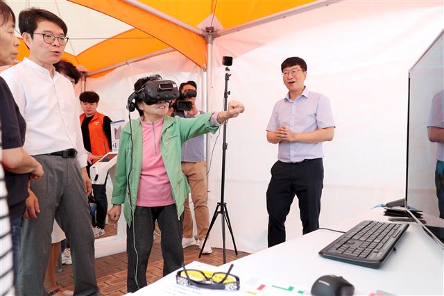 정원오(왼쪽) 서울 성동구청장이 지난 25일 구청 앞마당에서 열린 ‘치매극복박람회’에 참석, 한 할머니와 함께 치매 예방 가상현실(VR) 체험을 하고 있다. 성동구 제공
