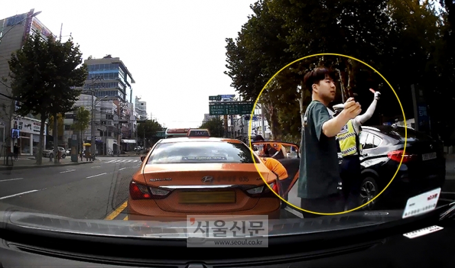 박상현씨가 지난 5일 오전 서울 서초구 서울고교 사거리 인근 도로에서 택시 안에 응급환자가 있는 것을 목격하고 119에 신고했다. 사진은 박씨가 수신호로 차량들의 서행을 유도하는 등 추가 사고 예방에 힘쓰고 있는 모습.