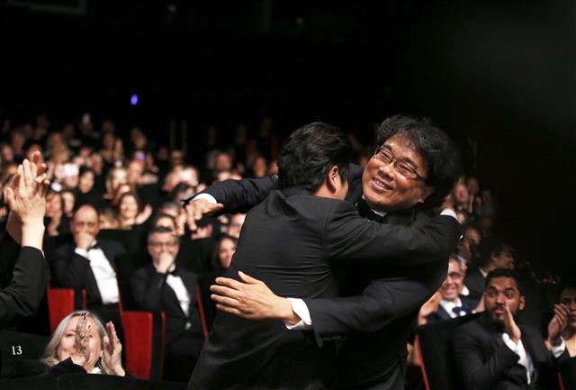 지난 5월 칸영화제에서 ‘기생충’이 대상인 황금종려상으로 호명된 뒤 주연 배우 송강호로부터 축하를 받는 봉준호 감독. 로이터 연합뉴스