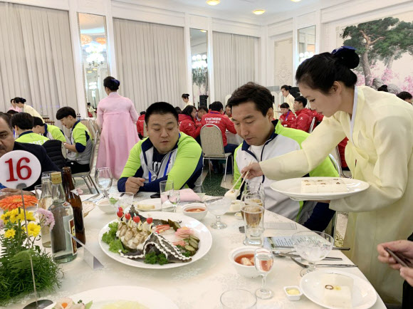 지난 28일 오후 평양 옥류관에서 열린 2019 아시아 유소년·주니어 역도선수권 대회 고별 만찬에서 종업원이 음식을 덜어주는 것을 우리 선수들이 유심히 보고 있다. 사진공동취재단 