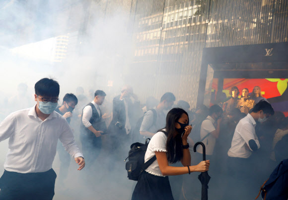 홍콩 경찰이 11일 도심 한복판에서 시위를 진압하기 위해 발사한 최루탄 연기가 자욱한 가운데 시민들이 코를 막고 괴로워하며 지나가고 있다. 홍콩 로이터 연합뉴스