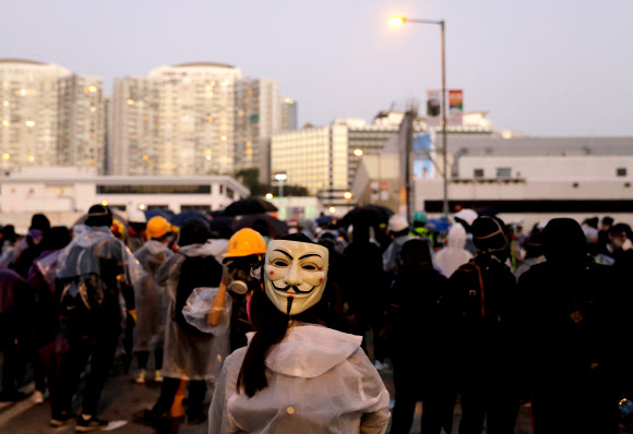 가이 포크스 가면을 쓴 홍콩 시민이 17일 홍콩 이공대 캠퍼스 밖에서 경찰과 시위대가 충돌한 가운데 크로스 하버 터널 위 다리에 서 있다. 2019.11.17  로이터 연합뉴스